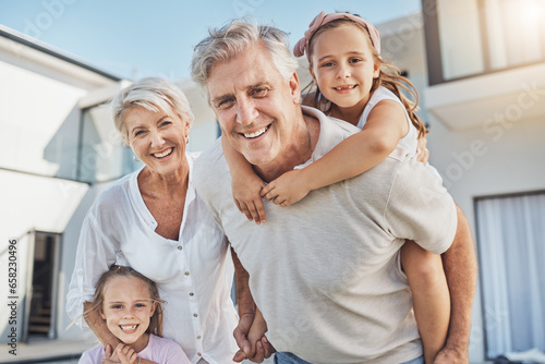 Happy, portrait and grandparents with girl children playing in the backyard of family home. Smile, love and kids bonding and having fun with grandmother and grandfather in the garden at modern house.