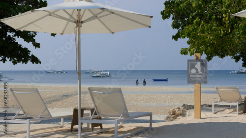 sandy beach with comfortable sun beds and umbrellas on a tropical island  on a sunny day  calm