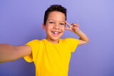 Photo of satisfied friendly boy wear yellow stylish clothes demonstrate v-sign isolated on purple color background