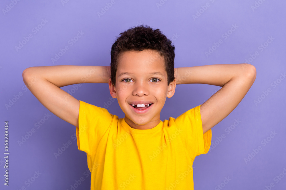 Photo of cheerful nice cute boy wear trendy clothes hold arms behind head enjoy rest isolated on purple color background Photo of cheerful nice cute boy wear trendy clothes hold arms behind head enjoy rest isolated on purple color background