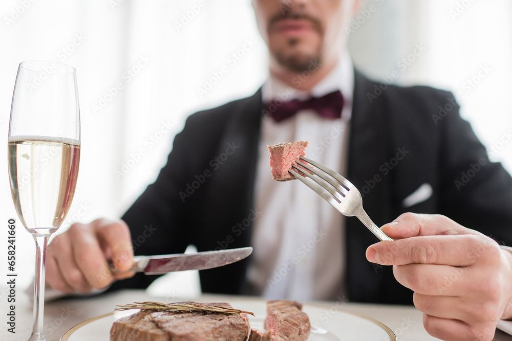 cropped view of wealthy gentleman in tuxedo holding cutlery with tasty cooked beef steak, close up cropped view of wealthy gentleman in tuxedo holding cutlery with tasty cooked beef steak, close up