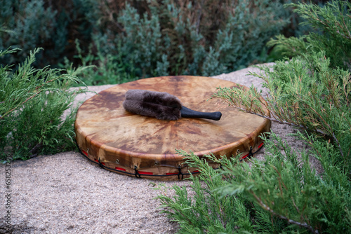 A shaman's tambourine made of genuine leather lies on a stone.