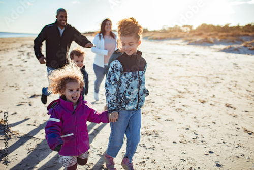 Young mixed family walking on the beach during a sunny winter day photo