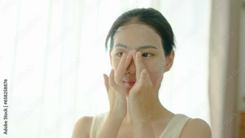 Beautiful young asian woman applying sheet facial mask and looking mirror at home, Girl applying cosmetic and makeup with skincare face for wrinkle, treatment and moisturizer, health and wellness Beautiful young asian woman applying sheet facial mask and looking mirror at home, Girl applying cosmetic and makeup with skincare face for wrinkle, treatment and moisturizer, health and wellness