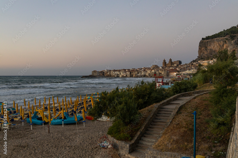 Obraz premium View of Cefalù, the city, the cathedral and its castle. Panorama seen from above of the whole landscape. Rough sea during sunset. The most beautiful places in Sicily. Excellent tourist destination.