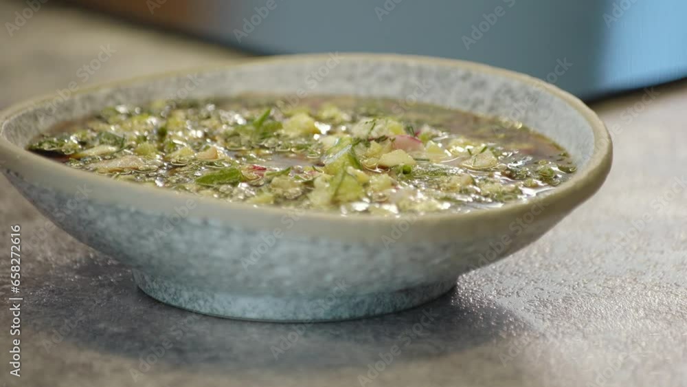 national traditional Russian dish - okroshka on a plate spinning on a wooden background. national traditional Russian dish - okroshka on a plate spinning on a wooden background.