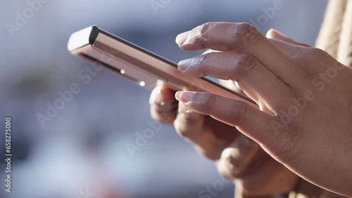 Close shot of female hands using a touch screen cell phone outdoors in the city 
