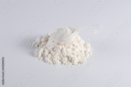 Protein with plastic measuring spoon on white background