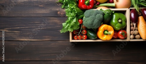 Assorted healthy food options in a paper box fruits vegetables herbs legumes cereals on wooden background Concept of clean eating and cooking Top view