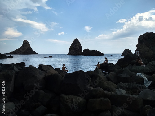 Panoramic view of the fascinating rocks of Aci Trezza on the Sicilian coast. These imposing volcanic boulders rise from the crystal-clear waters, creating a captivating seascape. photo