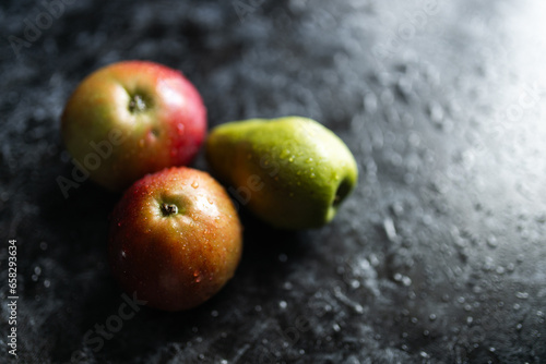 Apples, pears, green and purple grapes lie on a dark background. Organic fruit close-up. Fruits on a black background. Wet washed fruits on a black marble table