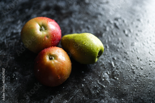 Apples, pears, green and purple grapes lie on a dark background. Organic fruit close-up. Fruits on a black background. Wet washed fruits on a black marble table