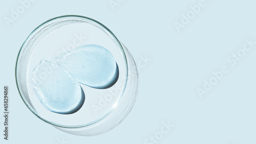 Petri dish and drops and ointments of transparent gel or serum on a blue background. Banner with empty space for advertising.