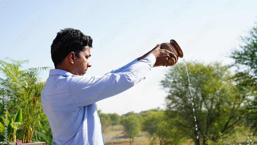 Young Indian man offering prayer to god on Terrence at home, early in the morning - obrazy, fototapety, plakaty 