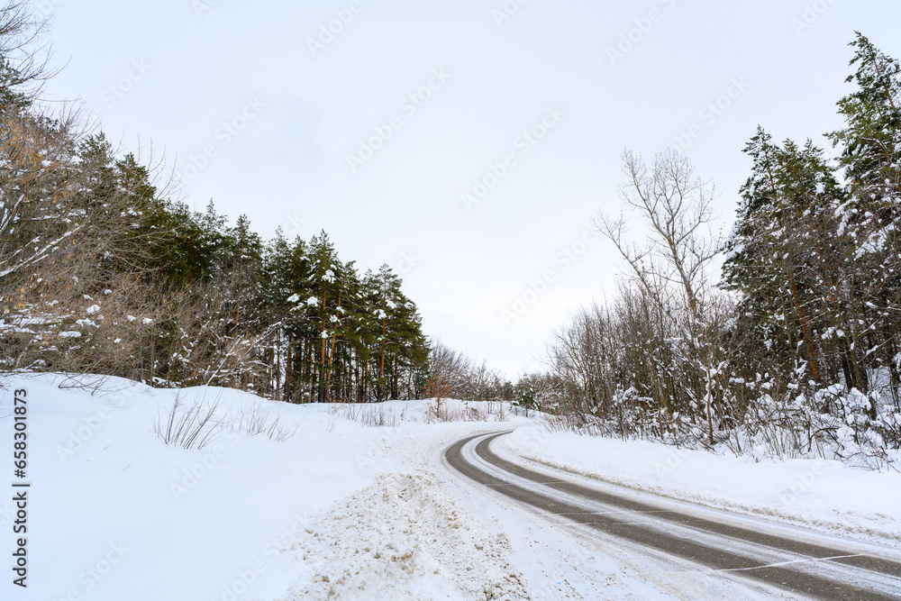 Snowy winter road in a mountain forest.
