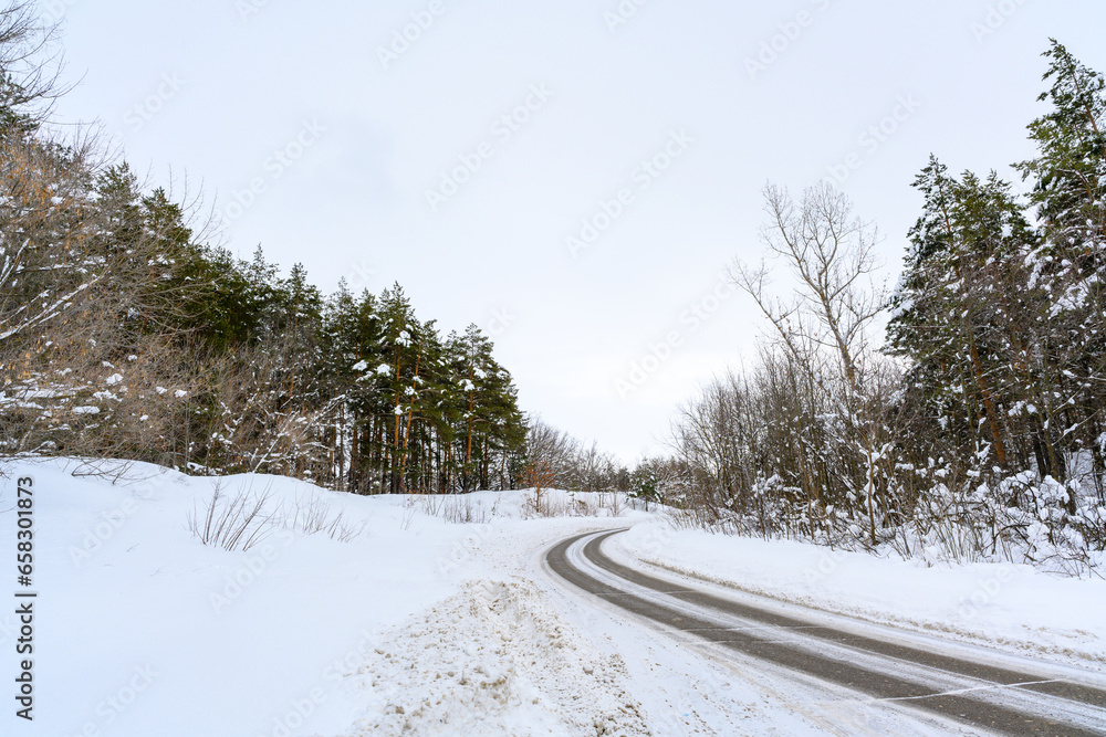 Obraz premium Snowy winter road in a mountain forest.