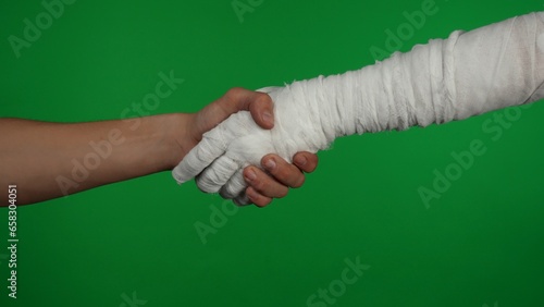 Detail green screen isolated chroma key photo capturing the mummy's hand reaching for the human hand. They are shaking their hands friendly.