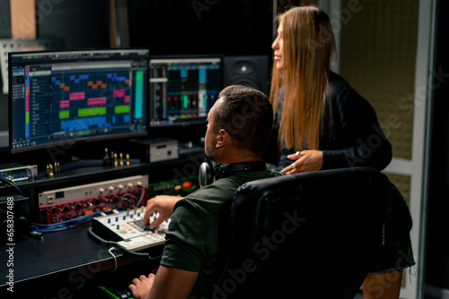 a girl singer and a male sound engineer work together in recording studio to create a new song