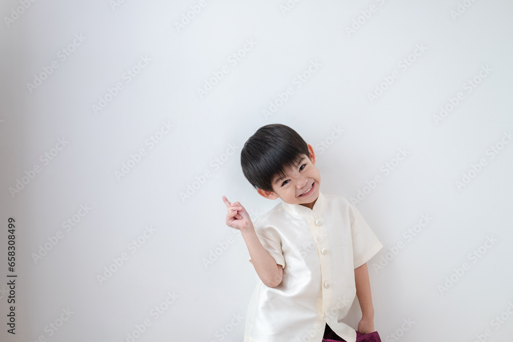 Asian boy Wearing traditional Thai clothing, standing with index finger upwards. on a white background Asian boy Wearing traditional Thai clothing, standing with index finger upwards. on a white background