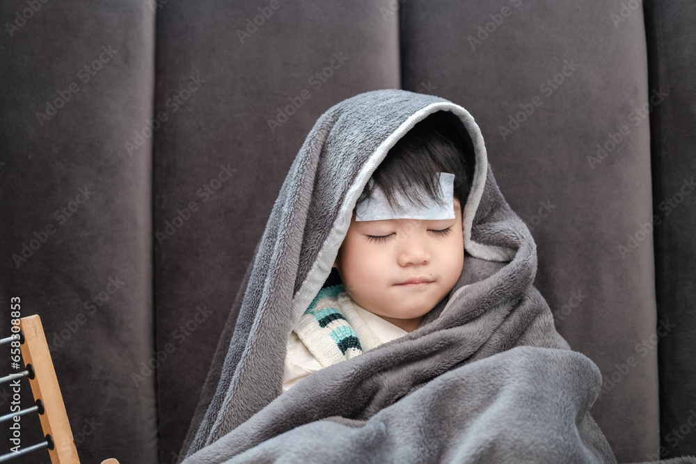 Asian boy Lying sick, he had a fever reducing patch on his forehead and covered himself with a blanket because of the cold. Asian boy Lying sick, he had a fever reducing patch on his forehead and covered himself with a blanket because of the cold.