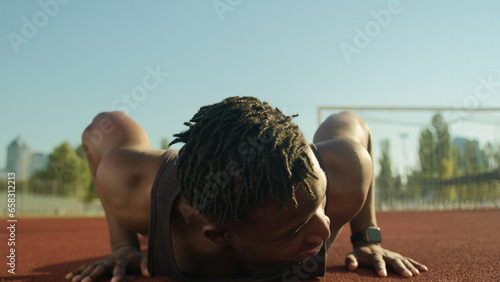 African American man sportsman muscular strong guy bodybuilder do push-ups exercise pumping biceps arms tired male athlete exhausted after workout outdoors on stadium sport health fitness motivation