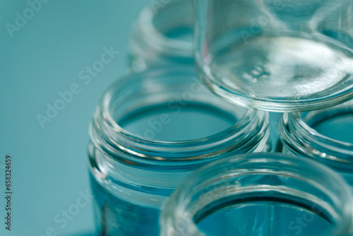 Empty glass jars with threaded rims and blue background