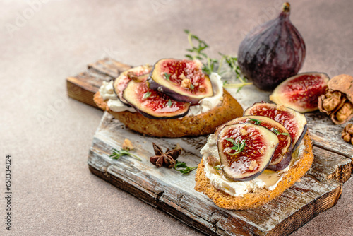 Bruschetta with fresh purple figs, ricotta cheese and honey on a wooden board, place for text, top view