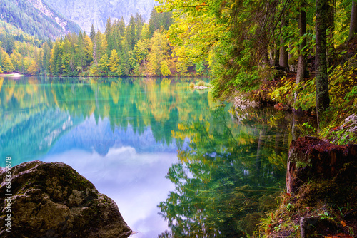 Laghi di Fusine inferior lake  Tarvisio  Italy. Amazing autumn landscape  crystal clear water with reflection and colored forest surrounded by Mangart mountain range  outdoor travel background