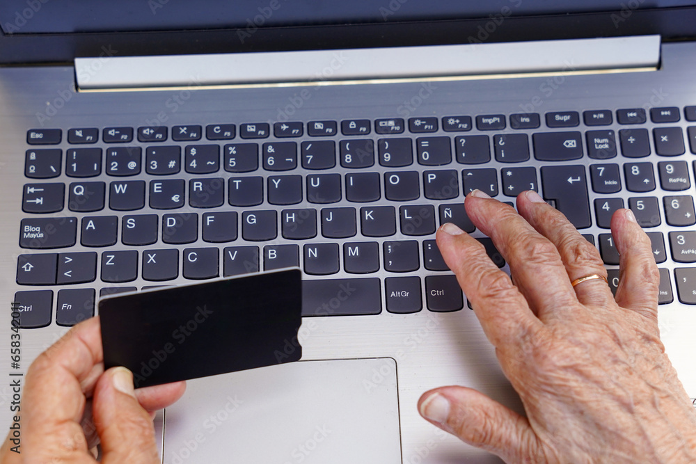 unrecognizable old woman shopping with a credit card online with a computer. Elderly with technology and internet unrecognizable old woman shopping with a credit card online with a computer. Elderly with technology and internet