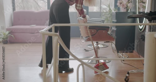 Ginger girl mopping the floor of the hairstyling studio after the haircut, trucking motion photo