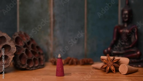 A smoke of stick burning and generating aromatic smoke surrounded by Buddha and eastern ornament items