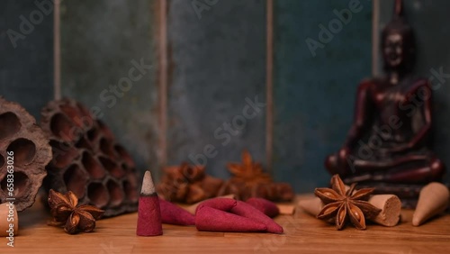 A smoke of stick burning and generating aromatic smoke surrounded by Buddha and eastern ornament items