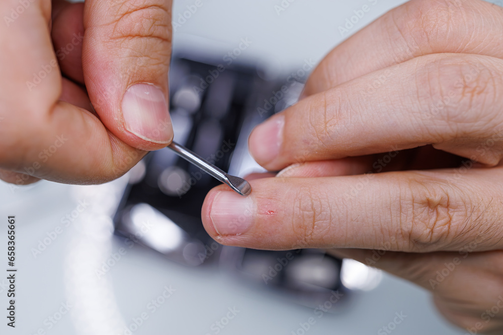 Scraping the nail with a tool. A man gives himself a manicure Scraping the nail with a tool. A man gives himself a manicure