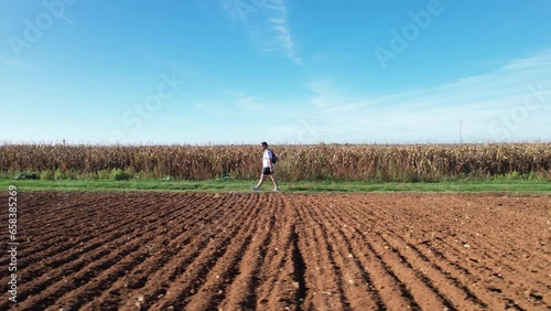 Homme qui marche sur un chemin au milieu des champs - vu depuis un drone - vu de coté - pratique de la randonnée photo