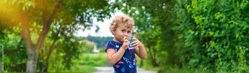 A child drinks water from a glass. Selective focus. A child drinks water from a glass. Selective focus.