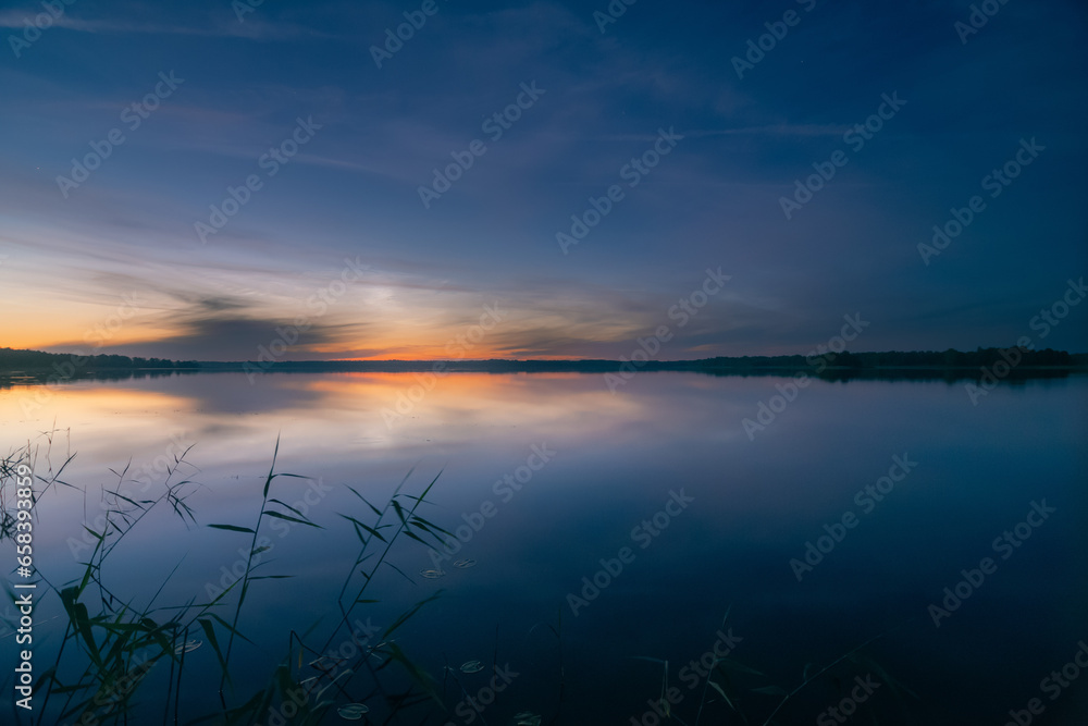Noctilucent clouds at night over lake