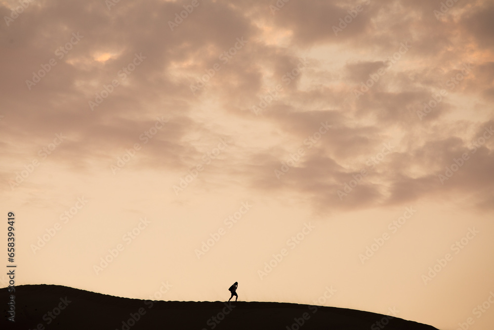 Person walking on the top of a dune during a sunset in Ica Peru