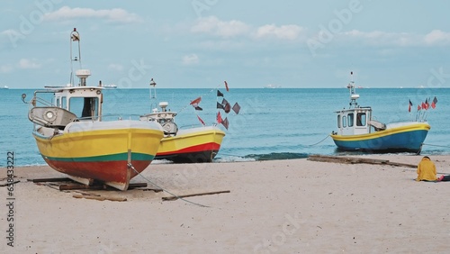 Fototapeta Naklejka Na Ścianę i Meble -  Undecked Handliner Fishing Vessel with Net Flags and Rusty Hooks Purse Sein Equipment Parked on Beach Sand at Seashore on Calm Day