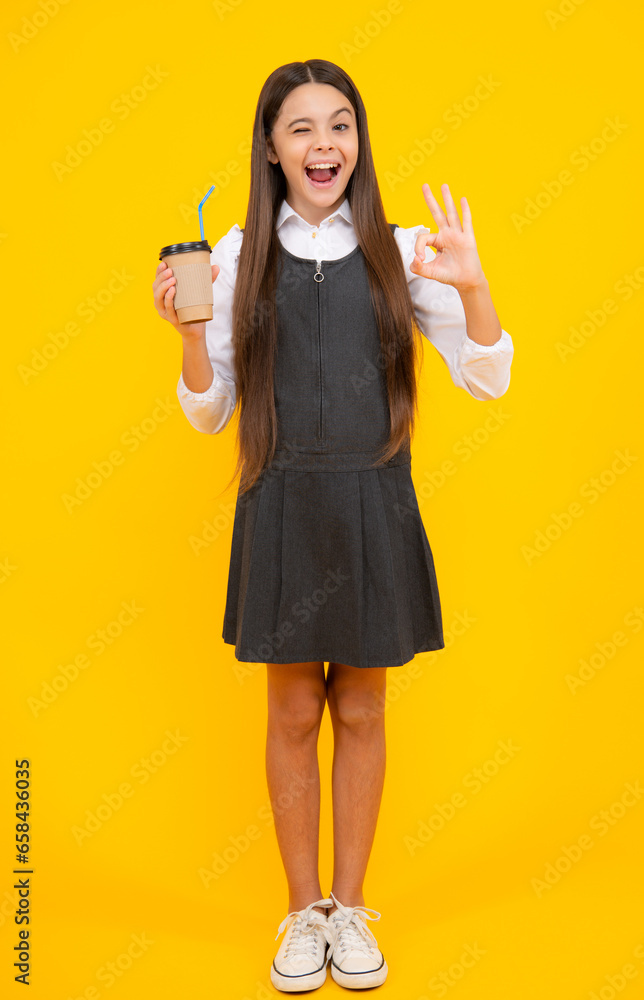 Amazed teen girl. Teenager girl holding a hot cup of coffee or tea. Child with takeaway cup on yellow background, morning energy drink beverage. Excited expression, cheerful and glad. Amazed teen girl. Teenager girl holding a hot cup of coffee or tea. Child with takeaway cup on yellow background, morning energy drink beverage. Excited expression, cheerful and glad.