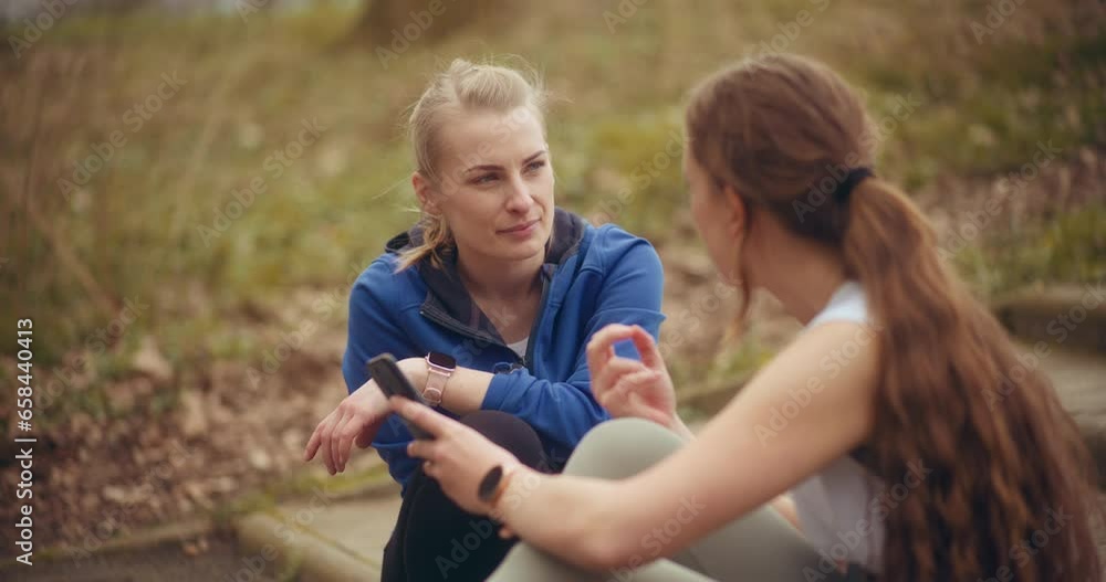 Woman talking with friend sharing mobile phone Woman talking with friend sharing mobile phone