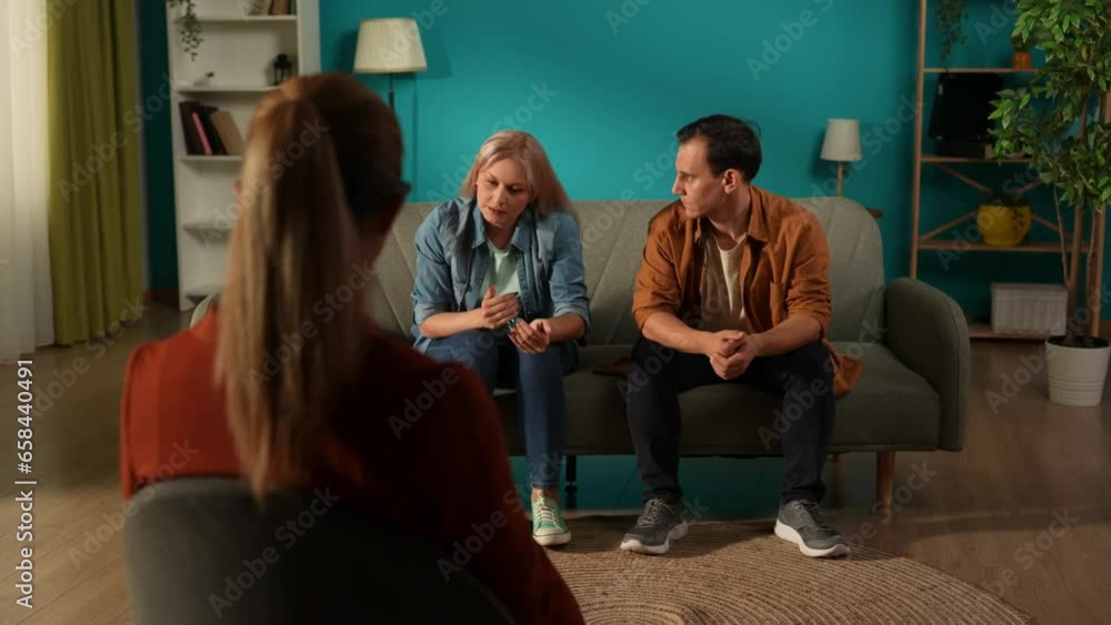 Conflicts in a relationship. A woman complaining about a man sitting next to her on a couch to a psychotherapist during a joint psychological session. The man gets angry, gets up and leaves. Conflicts in a relationship. A woman complaining about a man sitting next to her on a couch to a psychotherapist during a joint psychological session. The man gets angry, gets up and leaves.