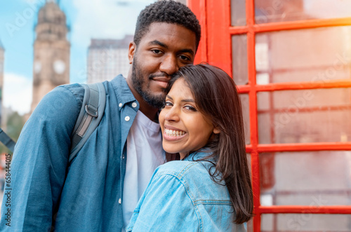 Valokuva two friend, couple using a camera,   taking selfie against a red phonebox, watching photos on camera, having a fun  in the city of England