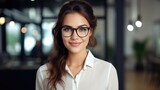 Young happy cheerful professional business woman wearing glasses looking at camera, close up face portrait indoors.