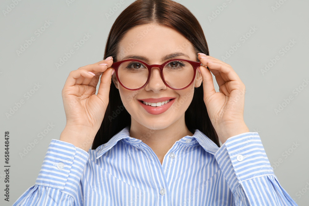 Portrait of smiling woman in stylish eyeglasses on grey background