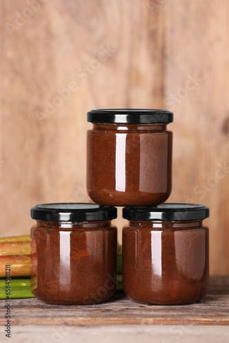 Jars of tasty rhubarb jam on wooden table