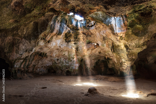 Quadiriki cave in Arikok National Park, Aruba. Sunbeams extend from openings in the cavern roof to the floor. 
 photo