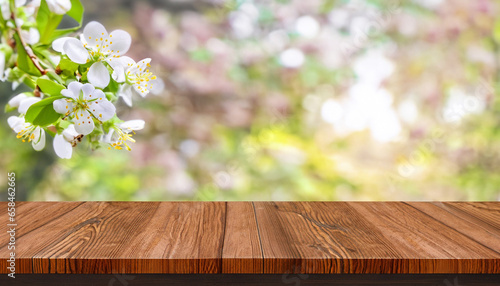 Spring background with white blossoms, sunlights in front of a wooden table and blurred background