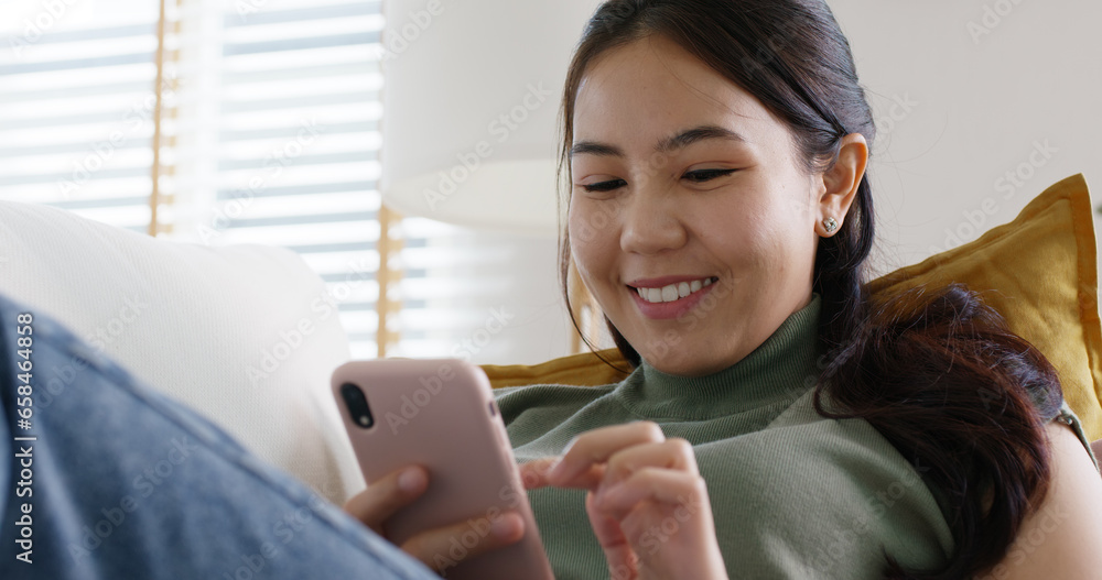 Young attractive beautiful casual asia female lady or student look at cellphone play social media IG reel tiktok app lying down at sofa couch living room feel relax comfort carefree at home apartment. Young attractive beautiful casual asia female lady or student look at cellphone play social media IG reel tiktok app lying down at sofa couch living room feel relax comfort carefree at home apartment.