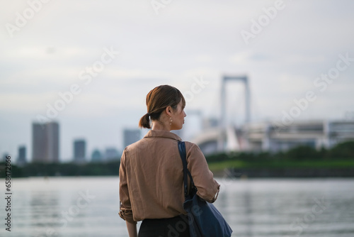 ベイエリアの景色を眺めるビジネスウーマンの後ろ姿