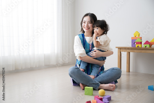 A preschool teacher and a child (caregiver) playing with building blocks Image of babysitter Full body
